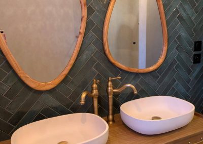 Salle de bain rénovée à garnerans avec zellige vert, miroirs en bois, meuble vasque en bois et robinetterie dorée mate